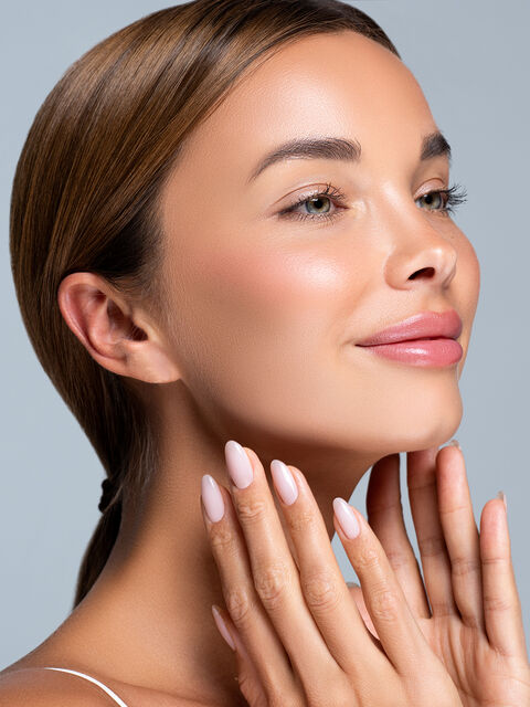 Woman with smooth, lifted facial contours resting her fingertips along her jawline