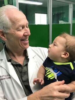 Dr. Nichter holding an infant patient during a Mission Plasticos surgical mission