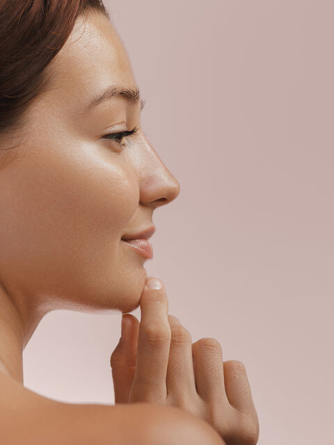 Profile of a woman with a defined chin and jawline, fingertips at her chin