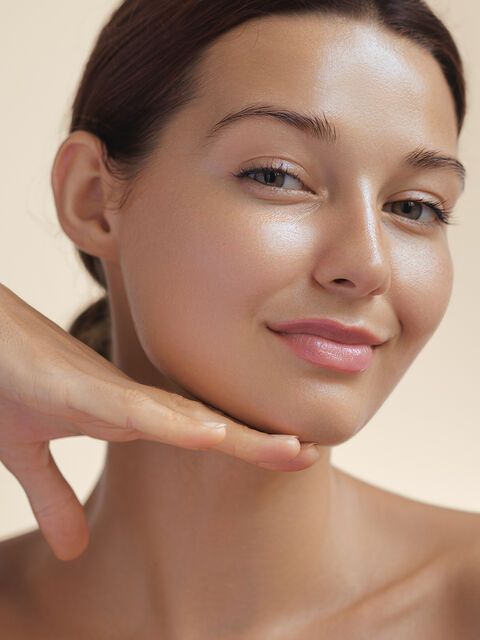 Close-up of a woman's face with her hand beneath her jawline, showing a firm, defined contour