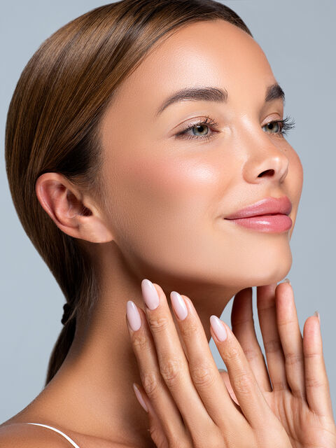 Woman with smooth, lifted facial contours resting her fingertips along her jawline